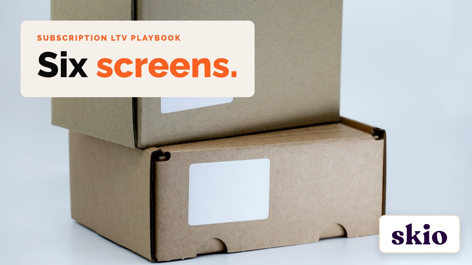 Two plain cardboard shipping boxes stacked on a white table, with a cream panel reading Six screens
